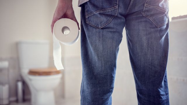 Man holding toilet paper roll in bathroom