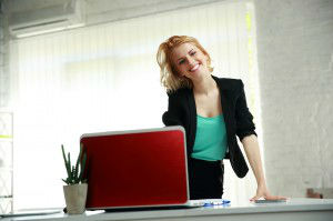 Young beautiful smiling woman leaning on the table in office