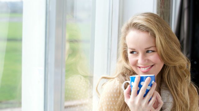 Smiling young lady holding cup of tea