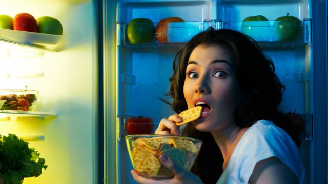 a hungry girl opens the fridge
