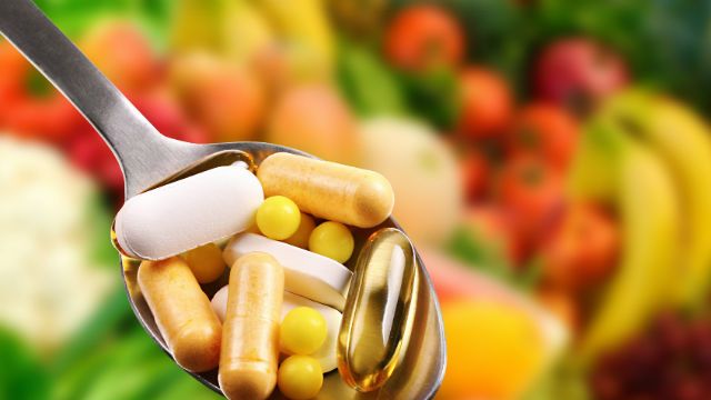 spoon with dietary supplements on fruits background