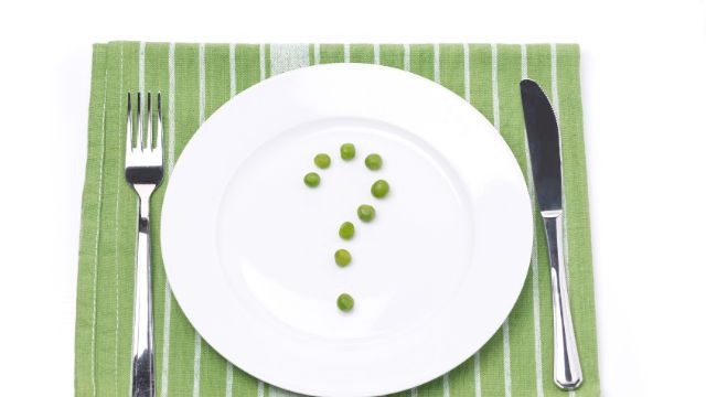 empty plate with green peas in the shape of a question mark