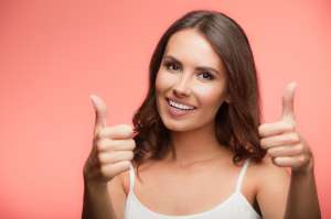 Smiling woman showing thumb up gesture, over red