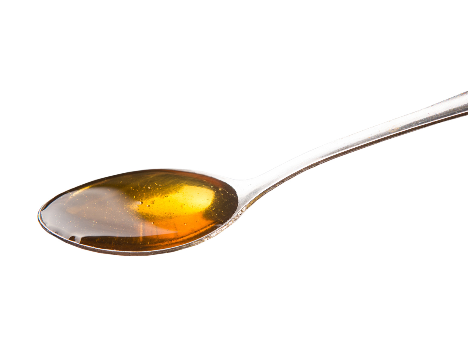 A spoon of honey over white background The Alternative Daily