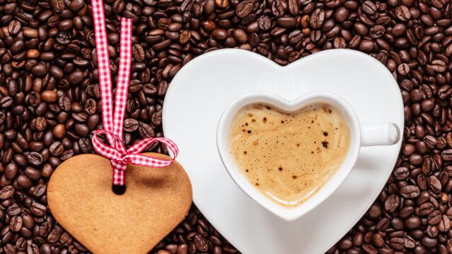 Heart shaped cup and cookie on coffee beans background