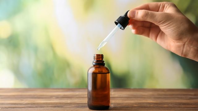 Female hand and bottle with eucalyptus essential oil on blurred background