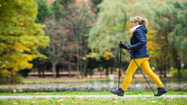 Nordic walking - middle-age woman working out in city park