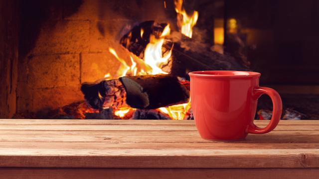 Red cup over fireplace on wooden table. Winter and Christmas holiday concept