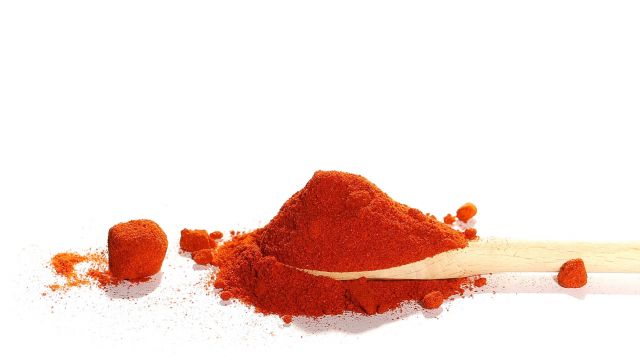cayenne pepper and wooden spoon isolated on white background