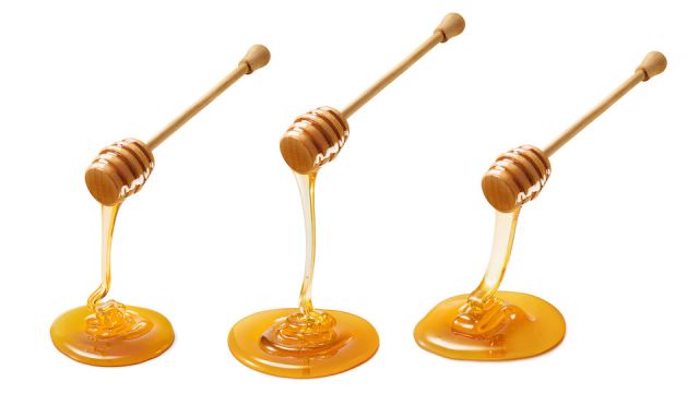 Set of wooden dippers with dripping honey isolated on white background