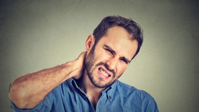 stressed, unhappy young handsome man with bad neck pain