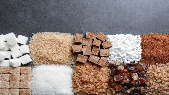 Flat lay composition with different types of sugar on gray background