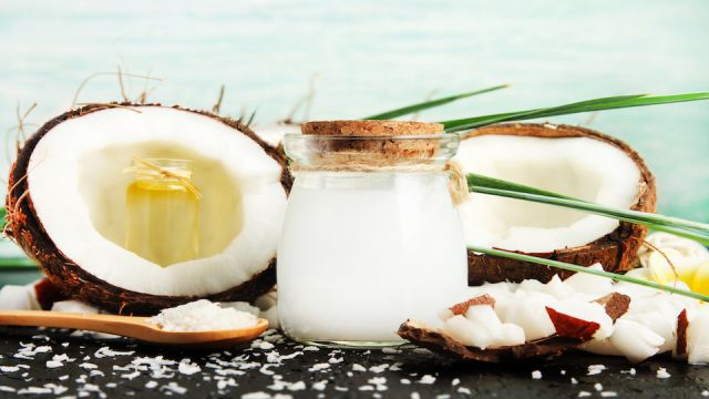 Coconut milk glass jar with nuts and oil bottles, fresh coconut flakes. Homemade skin & beauty care products rich in vitamins.