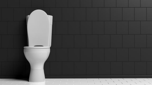 White toilet bowl on black wall background, copy space. 3d illustration