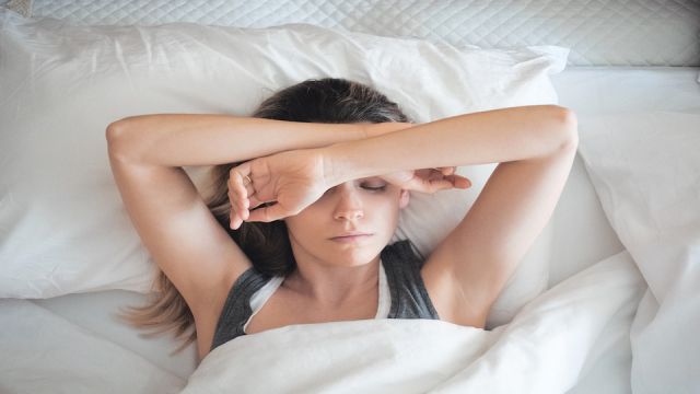 Donna a letto assonnata, sonno al mattino o stress