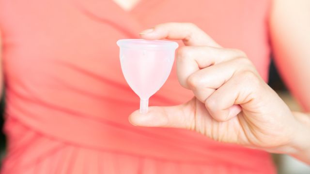 Zero waste concept - female holding menstrual cup in pink dress