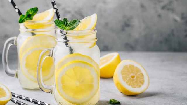 Homemade refreshing summer lemonade drink with lemon slices and ice in mason jars