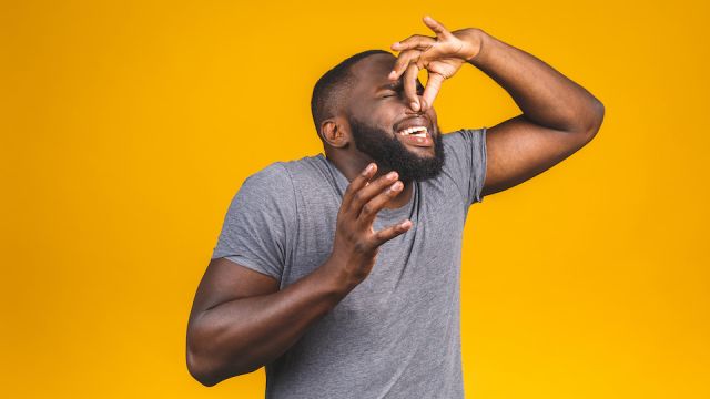 Afro american man isolated against yellow background smelling something stinky and disgusting, intolerable smell, holding breath with fingers on nose. Bad smells concept.