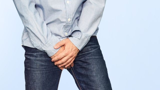Close up of a man with hands holding his crotch