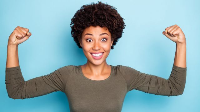 Portrait of amazed crazy mulatto girl show muscles impressed by her power scream wow omg wear casual style clothes isolated over blue color background