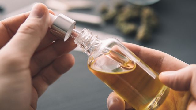 hemp product, Hand holding bottle of Cannabis oil in pipette, close up, natural herb, medical marijuana concept, CBD cannabis OIL.