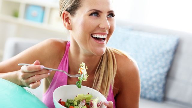 Young woman eating healthy salad after workout