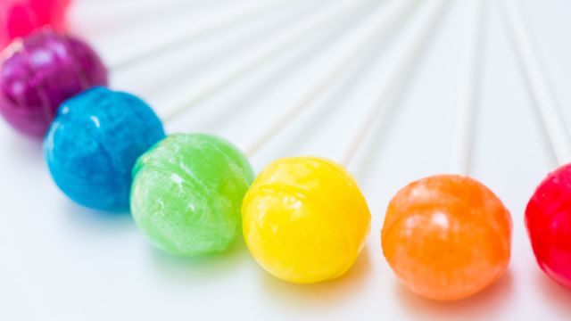 Rainbow design of sweet colorful lollipops against white background
