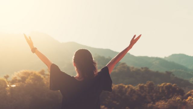 Copy space of woman rise hand up on top of mountain and sunset sky abstract background.