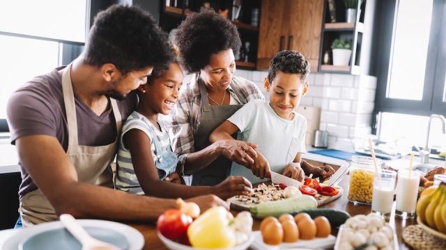 Happy african american family preparing healthy food together in kitchen