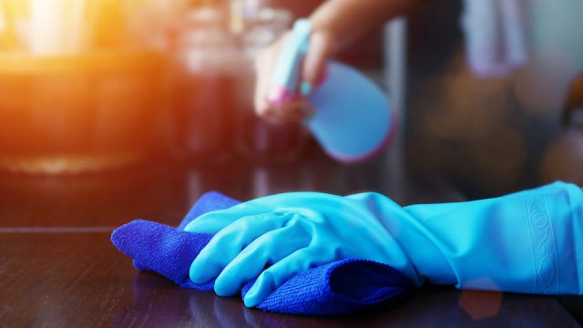 hand in blue rubber glove holding blue microfiber cleaning cloth and spray bottle with sterilizing solution make cleaning and disinfection for good hygiene