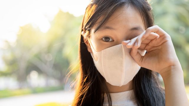 Asian child girl wearing protective mask,people rubbing the eyes due to air pollution,fine dust entering the eye,unclean hand,dirty hands,touch her eyes,risk of infection from spread of Covid-19 virus