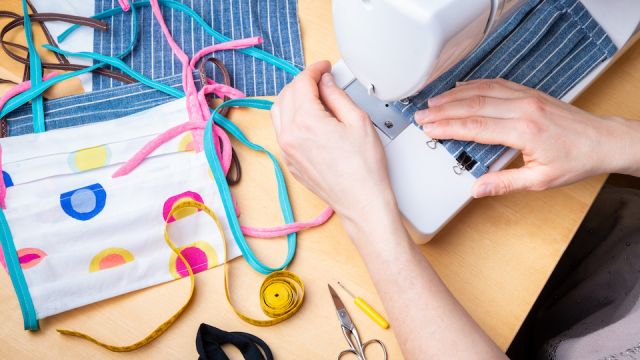Woman hands using the sewing machine to sew the face mask during the coronavirus pandemia. Domestic sewing due to the shortage of medical materials.