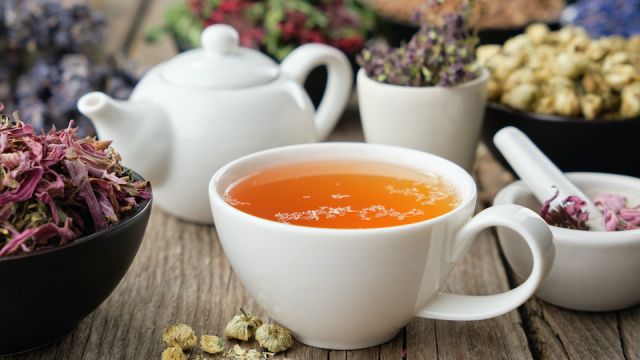 Healthy herbal tea cup. Teapot and medicinal herbs on table. Herbal medicine.