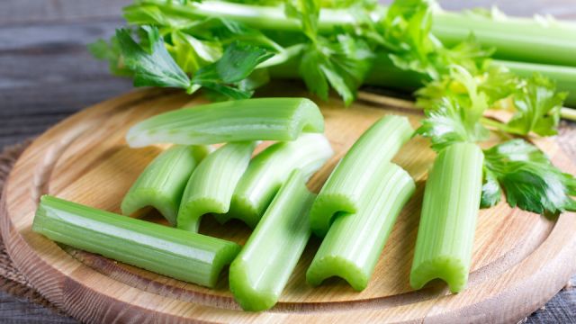 Fresh celery stems on wooden cutting board