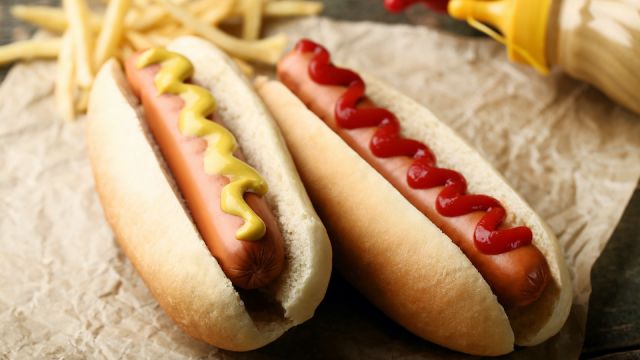 Hot dogs with mustard and ketchup on wooden table