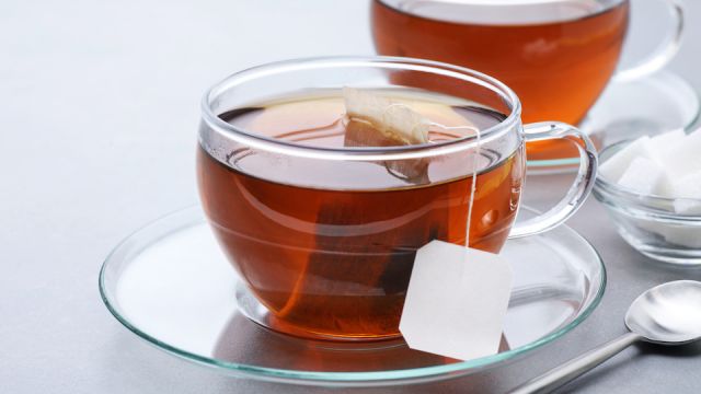 Cup of tea with tea bag on a gray background.