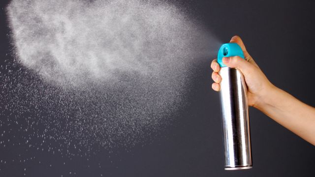 Sprayed air freshener in hand on grey background
