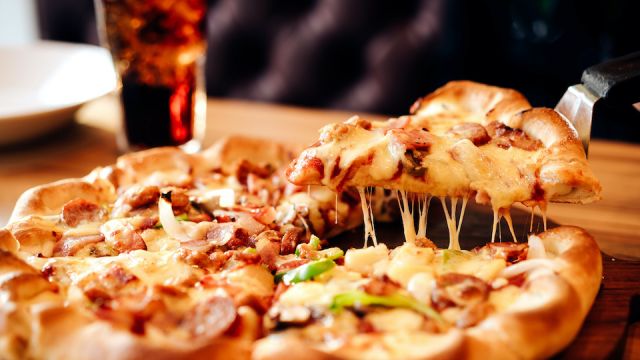 Slice of pizza cheese crust seafood topping sauce. with bell pepper vegetables delicious tasty fast food italian traditional and soft drink carbonated fresh on wooden board table classic in side view