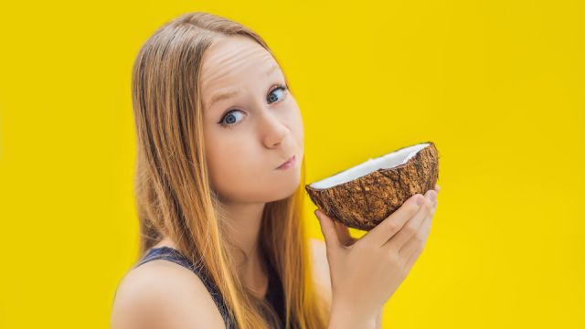Young woman doing oil pulling over yellow background