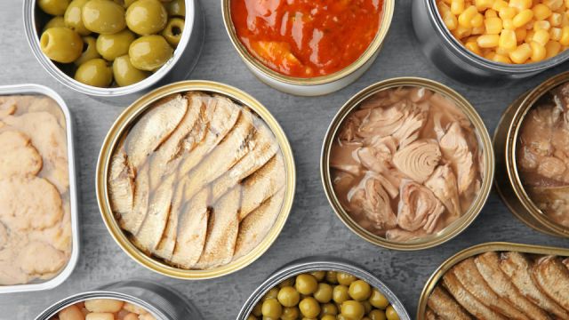 Open tin cans with different food on table